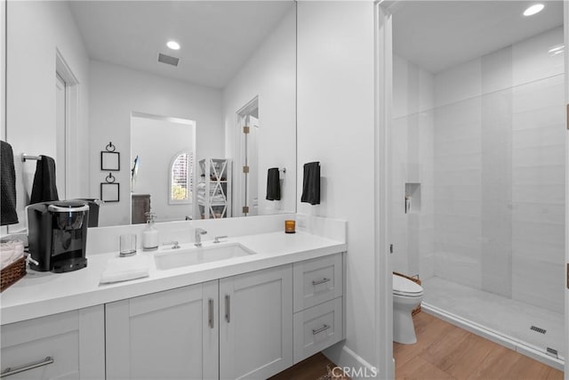 bathroom with a shower, wood-type flooring, vanity, and toilet