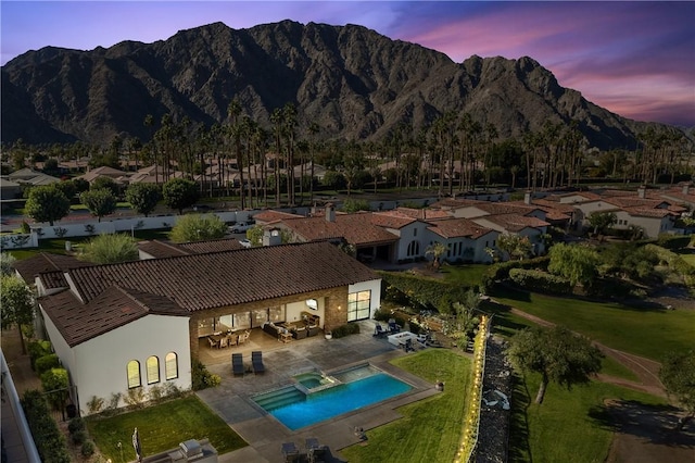 exterior space with a mountain view, a lawn, and a patio area