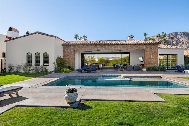 rear view of house featuring a yard, a mountain view, a pool with hot tub, and a patio