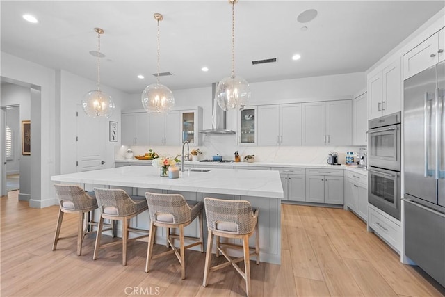 kitchen with white cabinetry, a breakfast bar area, backsplash, stainless steel appliances, and a center island with sink