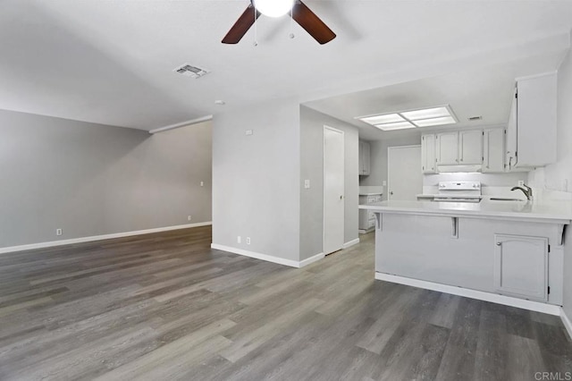 kitchen with sink, a kitchen breakfast bar, dark hardwood / wood-style floors, kitchen peninsula, and range