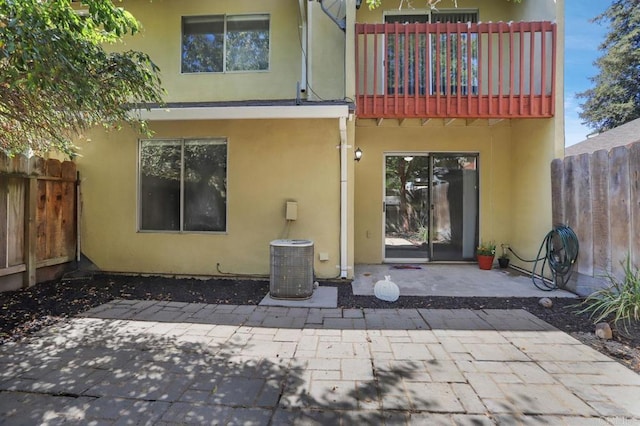 rear view of property with central air condition unit, a patio area, and a balcony