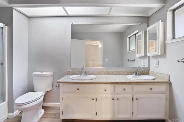 full bathroom with ceiling fan, toilet, wood-type flooring, and vanity