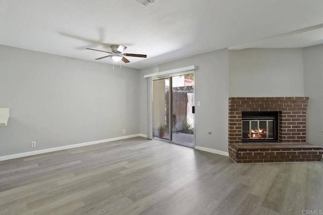 unfurnished living room with hardwood / wood-style floors, ceiling fan, and a fireplace