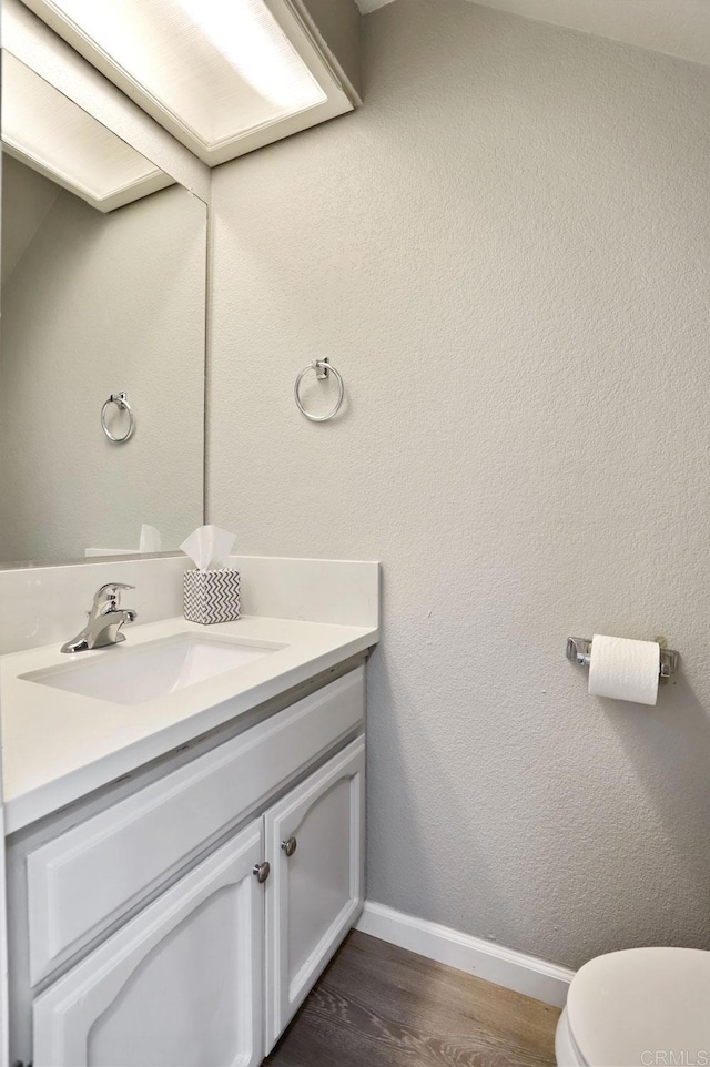 bathroom featuring toilet, vanity, and hardwood / wood-style flooring