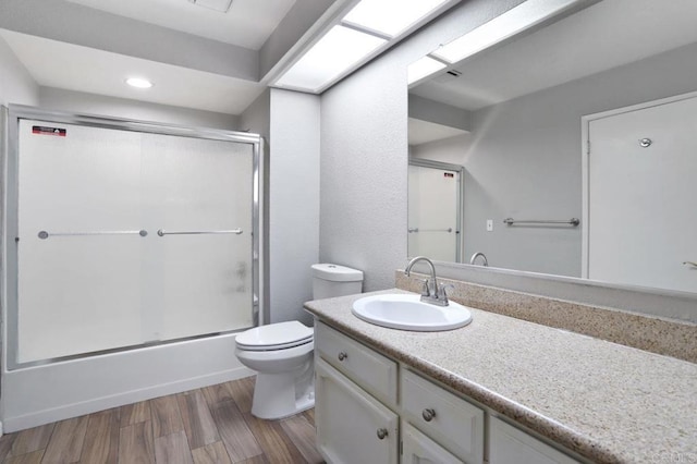 full bathroom featuring hardwood / wood-style flooring, vanity, toilet, and shower / bath combination with glass door