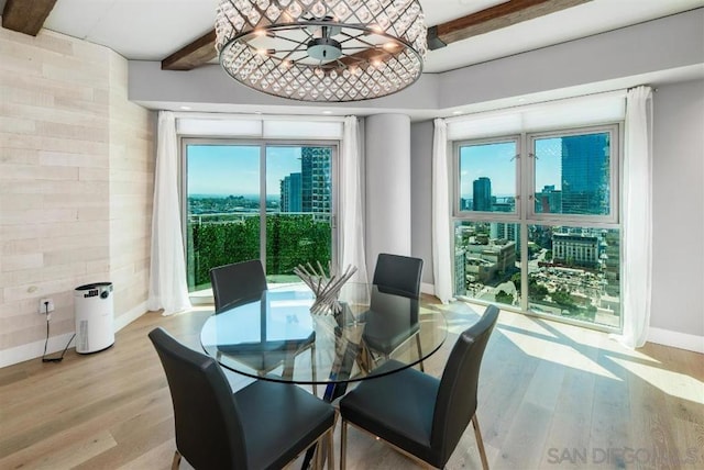 dining area featuring beamed ceiling, light hardwood / wood-style flooring, and a notable chandelier