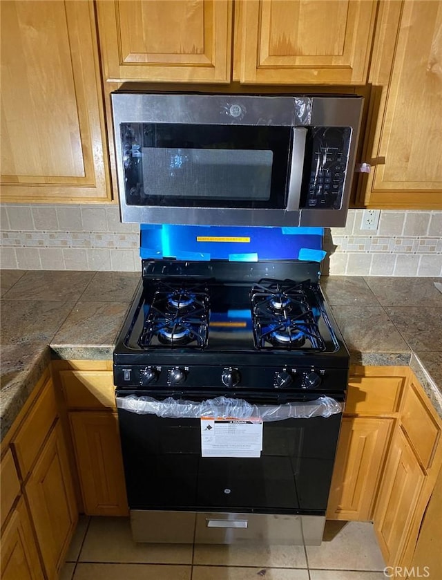 kitchen with tile patterned flooring, stainless steel appliances, and tasteful backsplash