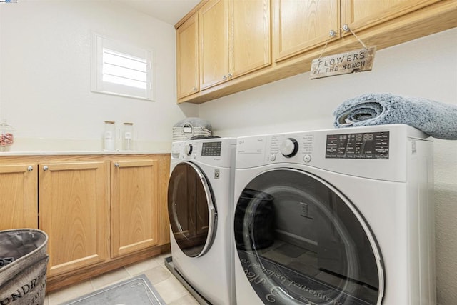 laundry room featuring cabinets, light tile patterned floors, and washing machine and clothes dryer