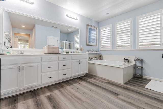 bathroom with plus walk in shower, vanity, hardwood / wood-style flooring, and plenty of natural light