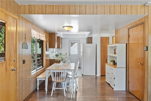 kitchen featuring white fridge, dark hardwood / wood-style flooring, and wooden walls