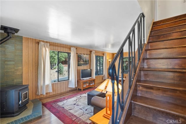 stairway featuring hardwood / wood-style floors, wood walls, and a wood stove