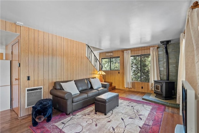 living room featuring hardwood / wood-style floors, wood walls, a wood stove, and heating unit