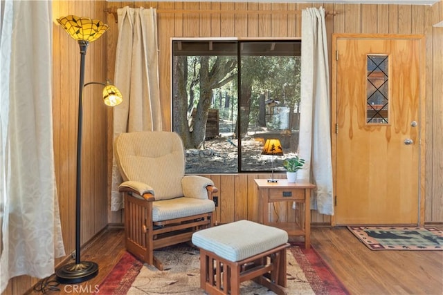 sitting room with wooden walls and dark wood-type flooring