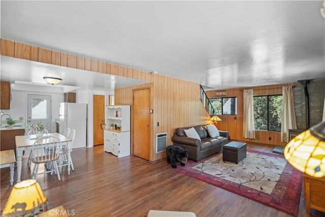 living room featuring wooden walls, a wood stove, and dark wood-type flooring