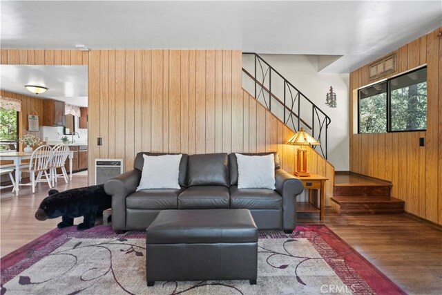 living room with hardwood / wood-style flooring, sink, and wooden walls