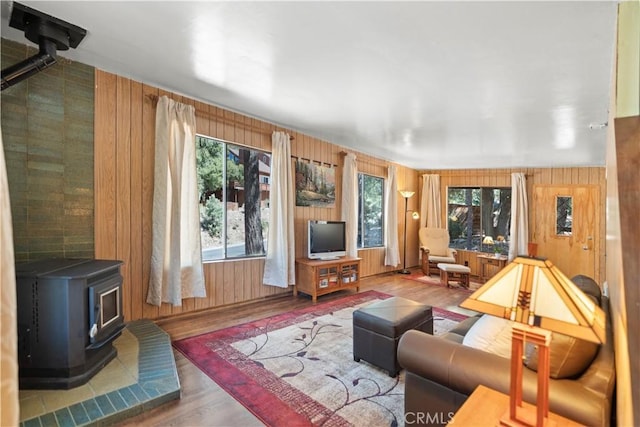 living room featuring a wood stove, a wealth of natural light, wood walls, and hardwood / wood-style flooring