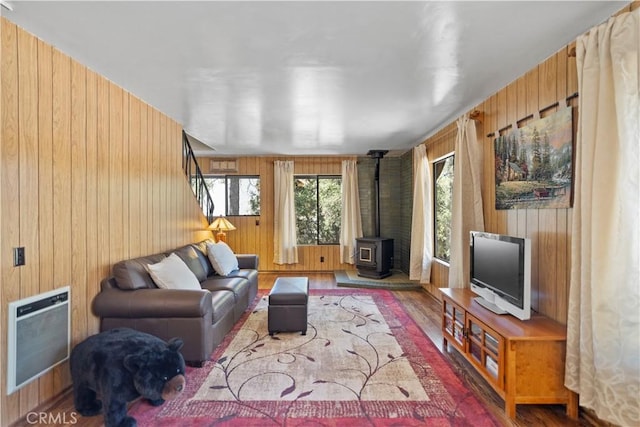 living room featuring hardwood / wood-style floors, wood walls, a wood stove, and heating unit