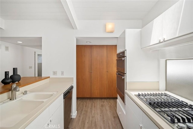 kitchen featuring white cabinets, appliances with stainless steel finishes, light hardwood / wood-style flooring, and beam ceiling