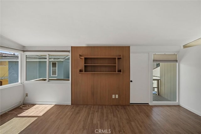 unfurnished bedroom with multiple windows and dark wood-type flooring