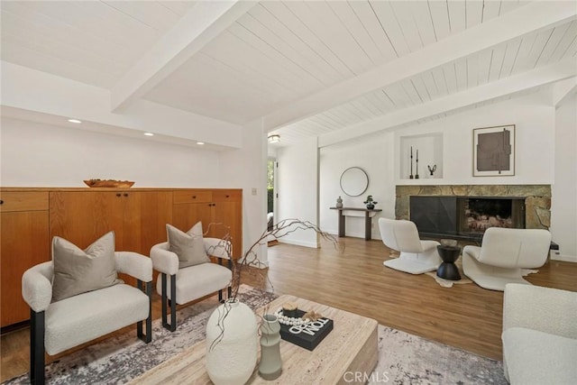 living room with hardwood / wood-style flooring, wood ceiling, a fireplace, and beamed ceiling