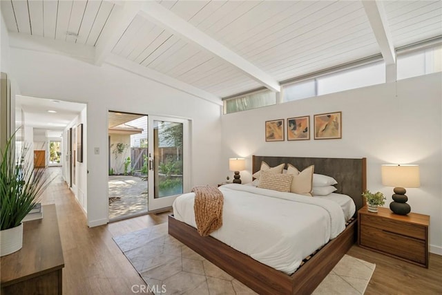 bedroom with access to exterior, lofted ceiling with beams, and light hardwood / wood-style flooring