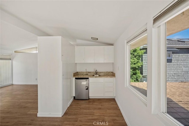 kitchen with lofted ceiling, white cabinets, stainless steel dishwasher, and dark hardwood / wood-style floors