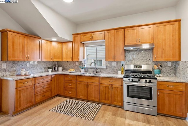 kitchen featuring light stone countertops, gas stove, and sink