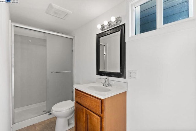 bathroom featuring toilet, vanity, tile patterned flooring, and a shower with door