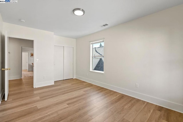 unfurnished bedroom with a closet and light hardwood / wood-style floors