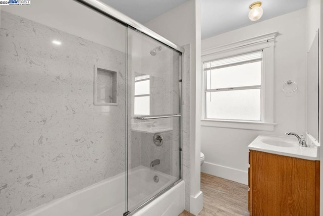 full bathroom featuring hardwood / wood-style flooring, toilet, vanity, and shower / bath combination with glass door