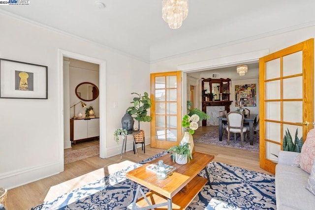 living room featuring light wood-type flooring, a notable chandelier, and crown molding