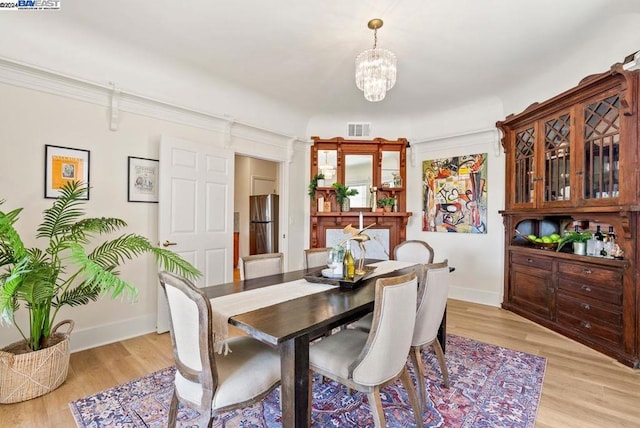 dining area featuring light hardwood / wood-style floors and a notable chandelier