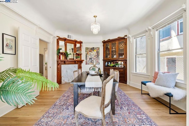 dining area with light hardwood / wood-style flooring and a notable chandelier