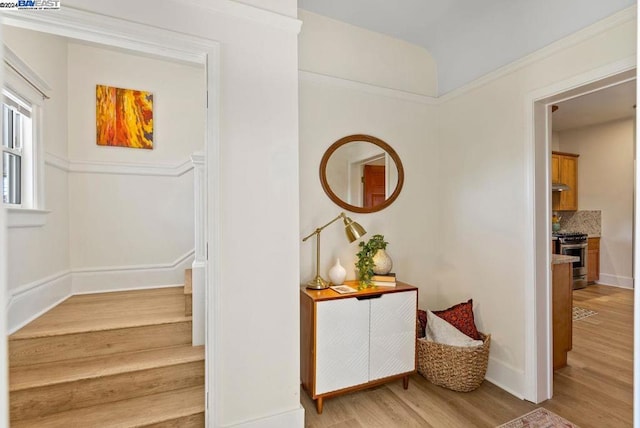 stairs with wood-type flooring and ornamental molding