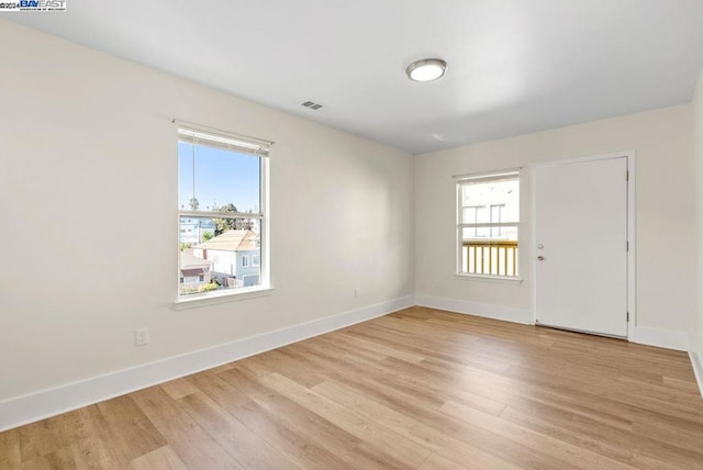 unfurnished room with light wood-type flooring and a wealth of natural light