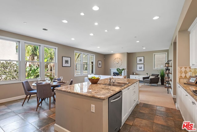 kitchen featuring decorative backsplash, a kitchen island with sink, sink, dishwasher, and white cabinets