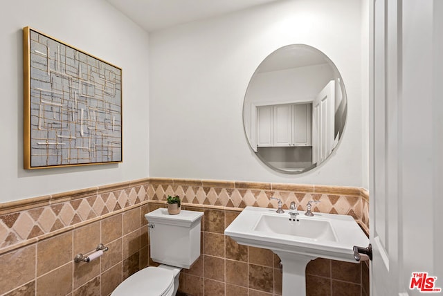 bathroom featuring sink, toilet, and tile walls