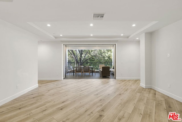 unfurnished room with a tray ceiling and light wood-type flooring