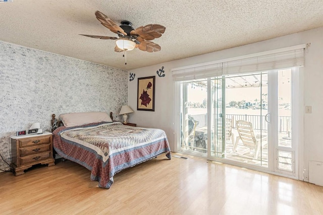 bedroom with a textured ceiling, access to outside, ceiling fan, and wood-type flooring