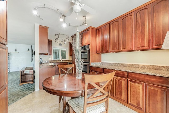 kitchen featuring double oven, light stone countertops, and ceiling fan