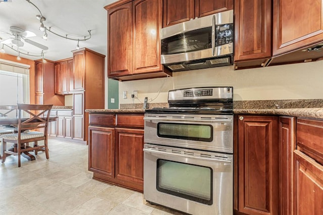 kitchen with ceiling fan, stainless steel appliances, dark stone countertops, and rail lighting