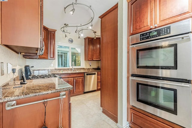 kitchen with light stone countertops, stainless steel appliances, and sink