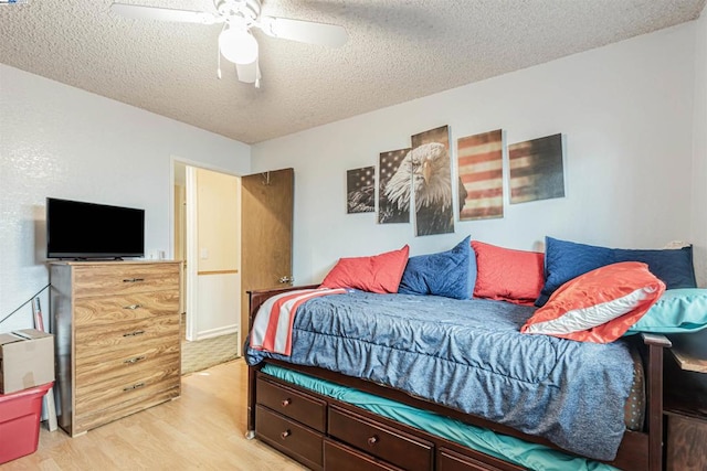 bedroom with light hardwood / wood-style floors, ceiling fan, and a textured ceiling