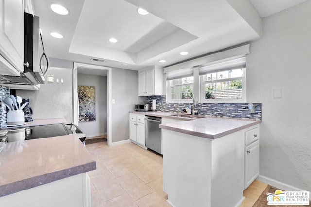 kitchen featuring white cabinets, a tray ceiling, appliances with stainless steel finishes, and sink