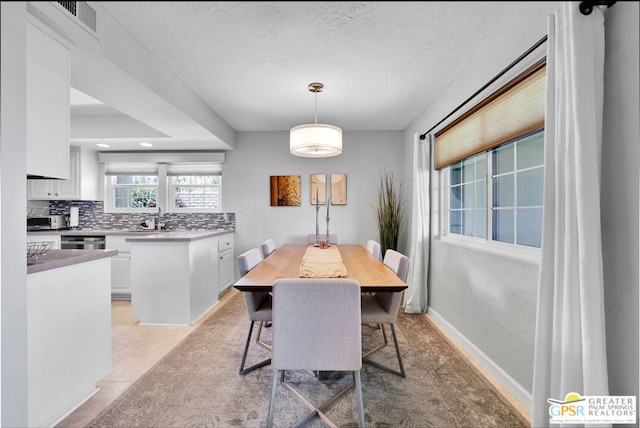 dining room with a textured ceiling, light tile patterned floors, and sink