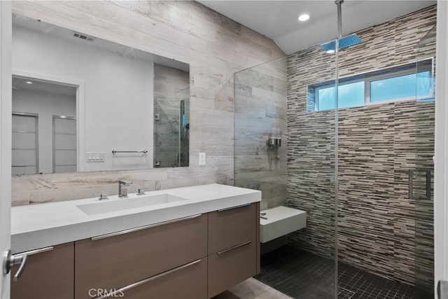 bathroom featuring vanity, tile patterned floors, walk in shower, and tile walls