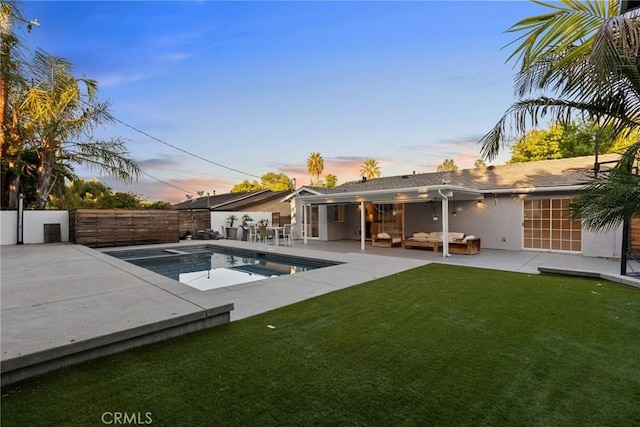 pool at dusk with a yard, an outdoor living space, and a patio area