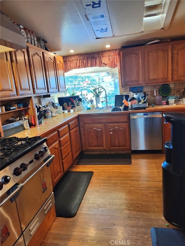 kitchen featuring decorative backsplash, stainless steel appliances, light hardwood / wood-style floors, and sink