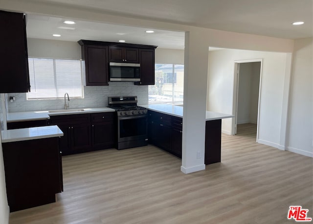 kitchen with light hardwood / wood-style floors, backsplash, stainless steel appliances, dark brown cabinetry, and sink